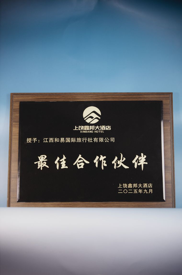 Shangrao Xinbang Hotel 2025 Best Partner (最佳合作伙伴) black-and-gold rosewood-framed plaque presented to Jiangxi Heyi International Travel, dated September 2025